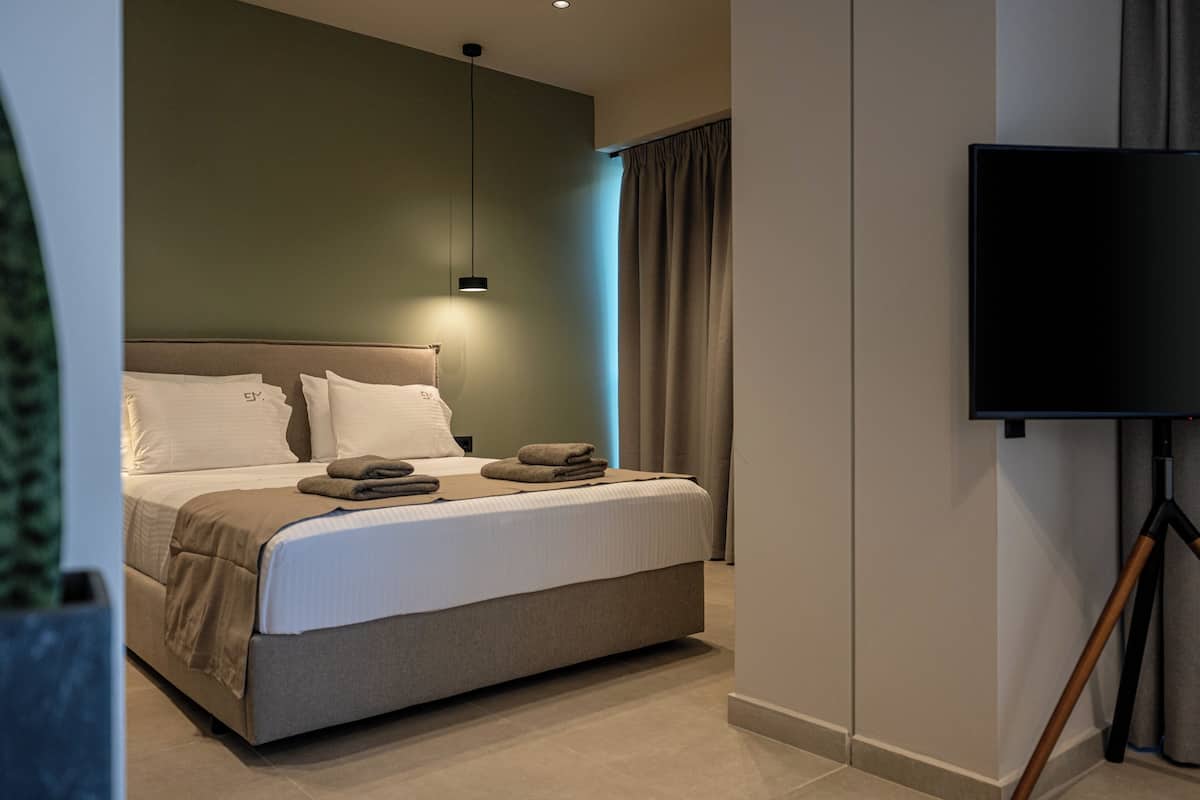 Ein modernes Hotelzimmer mit einem großen Bett, einem Flachbildfernseher und einer Deckenleuchte.