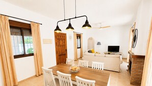 Ein Essbereich mit Holztisch, weißen Stühlen und einer Pendelleuchte.