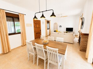 Ein Essbereich mit Holztisch, weißen Stühlen und einer Pendelleuchte.