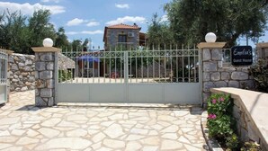 A gated entrance with a stone wall and a sign indicating 'Emilia's Guest House.' - Emilia's Guest House with Sea View Balcony, Stoupa (Stoupa)