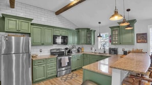 A kitchen with green cabinets, stainless steel appliances, and a granite countertop. - Rustic Woodland Cabin | Hot Tub | Cozy Escape (Lake Harmony)