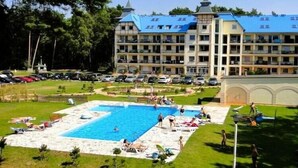 A hotel with a swimming pool, multiple balconies, and a landscaped garden. - Apartment with swimming pool, Lukecin (Łukęcin)