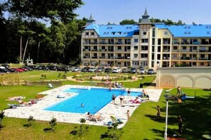 Ein Hotel mit Schwimmbad, mehreren Balkonen und einem angelegten Garten.