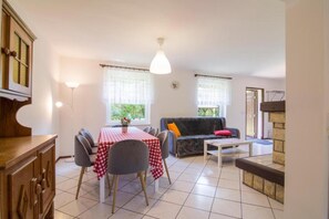 A dining area with a table set for two, a sofa, and a small coffee table. - Large holiday home with a garden in Lubiatów (Lubiatowo)