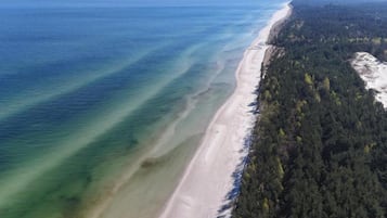 Vista aérea de uma praia com águas cristalinas e área arborizada.