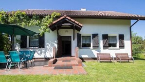 A house with a tiled porch, a door, and two windows with shutters. - Large holiday home with a garden in Lubiatów (Lubiatowo)