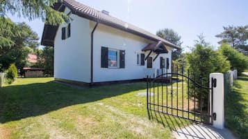 Uma casa térrea com fachada branca e telhado escuro.