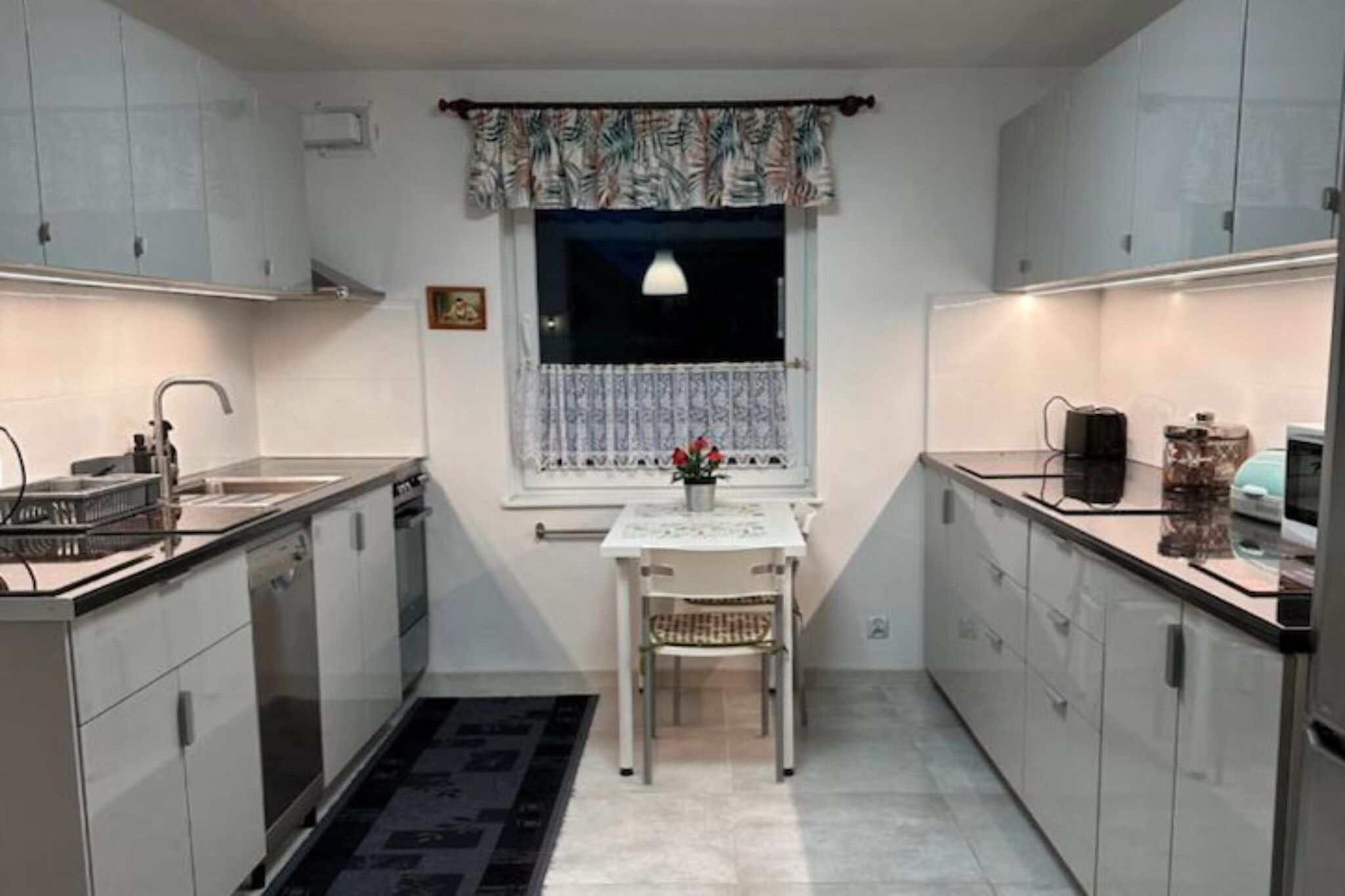 Cocina compacta con ventana, una mesa de comedor y una silla.