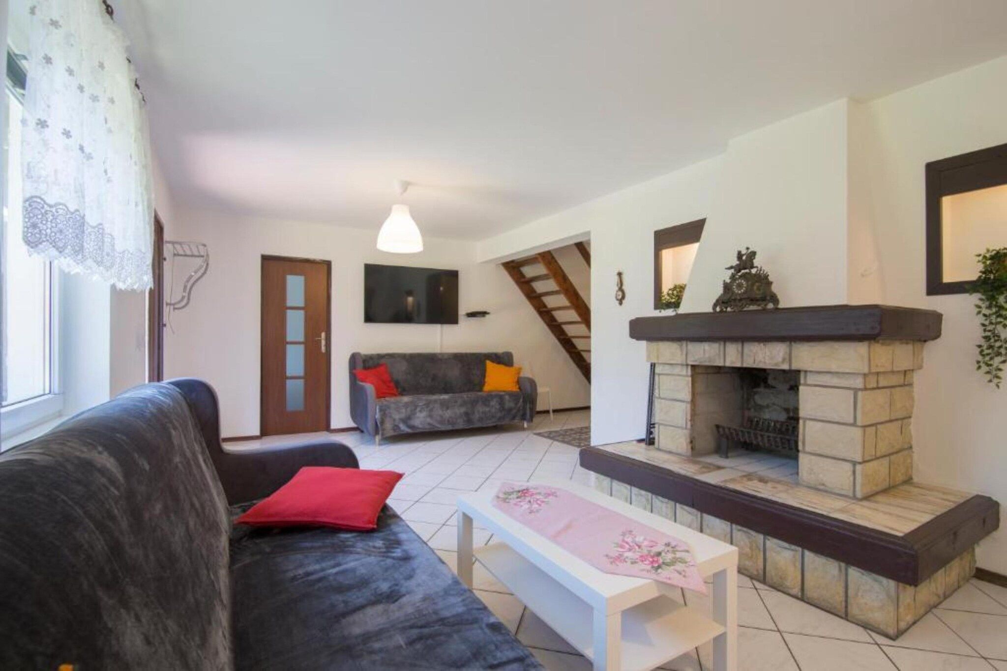 Una sala de estar con sofá, mesa, chimenea y escalera.