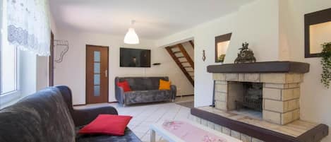 A living room with a sofa, a table, a fireplace, and a staircase.