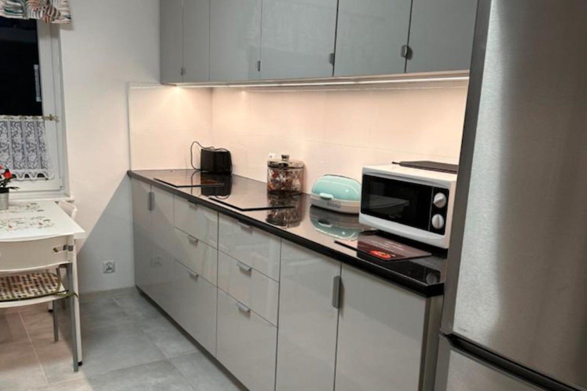 Una cocina con microondas, tostadora y cafetera sobre la encimera.