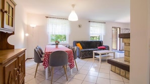 Uma sala de jantar com uma mesa posta para dois, um sofá e uma pequena mesa de centro.