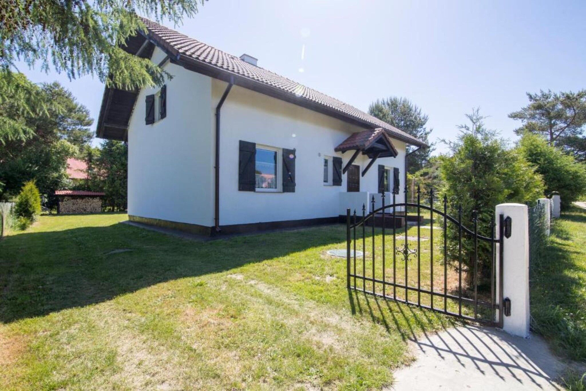 Une maison de plain-pied avec une façade blanche et un toit foncé.