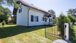 Uma casa térrea com fachada branca e telhado escuro.