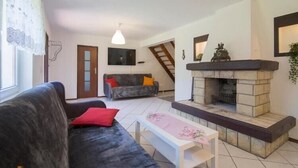 Un salon avec une cheminée, un canapé, une table basse et un escalier menant à un autre niveau.