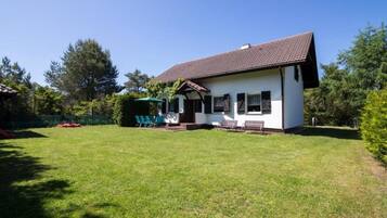 Einbungalow mit Ziegeldach, einer Veranda mit Bank und einem gepflegten Rasen.