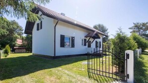 Une maison de plain-pied à l’extérieur blanc, avec un toit recouvert de tuiles et un portail en métal noir.