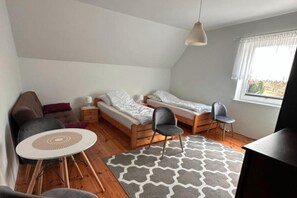 A small, compact room with a bed, two chairs, a small table, and a window. - Comfortable holiday home with a private garden (Lubiatowo)