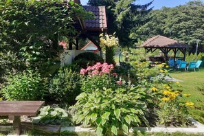 A garden with a gazebo, a wooden bench, and various plants. - Comfortable holiday home with a private garden (Lubiatowo)