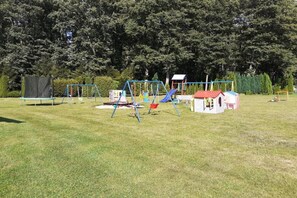 A playground with swings, slides, and a small house structure.