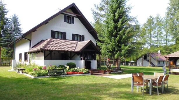 A two-story house with a sloped roof, a front porch, and a well-maintained lawn. - Comfortable holiday home with a private garden (Lubiatowo)