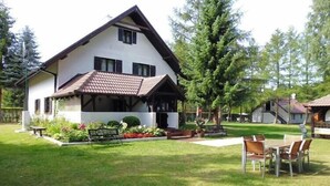 Una casa a due piani con tetto spiovente, un portico e un prato curato.