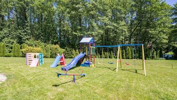 Une aire de jeux avec un toboggan, des balançoires et des structures d’escalade.