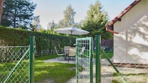 Un patio trasero cercado con un área de patio, una mesa y una silla.