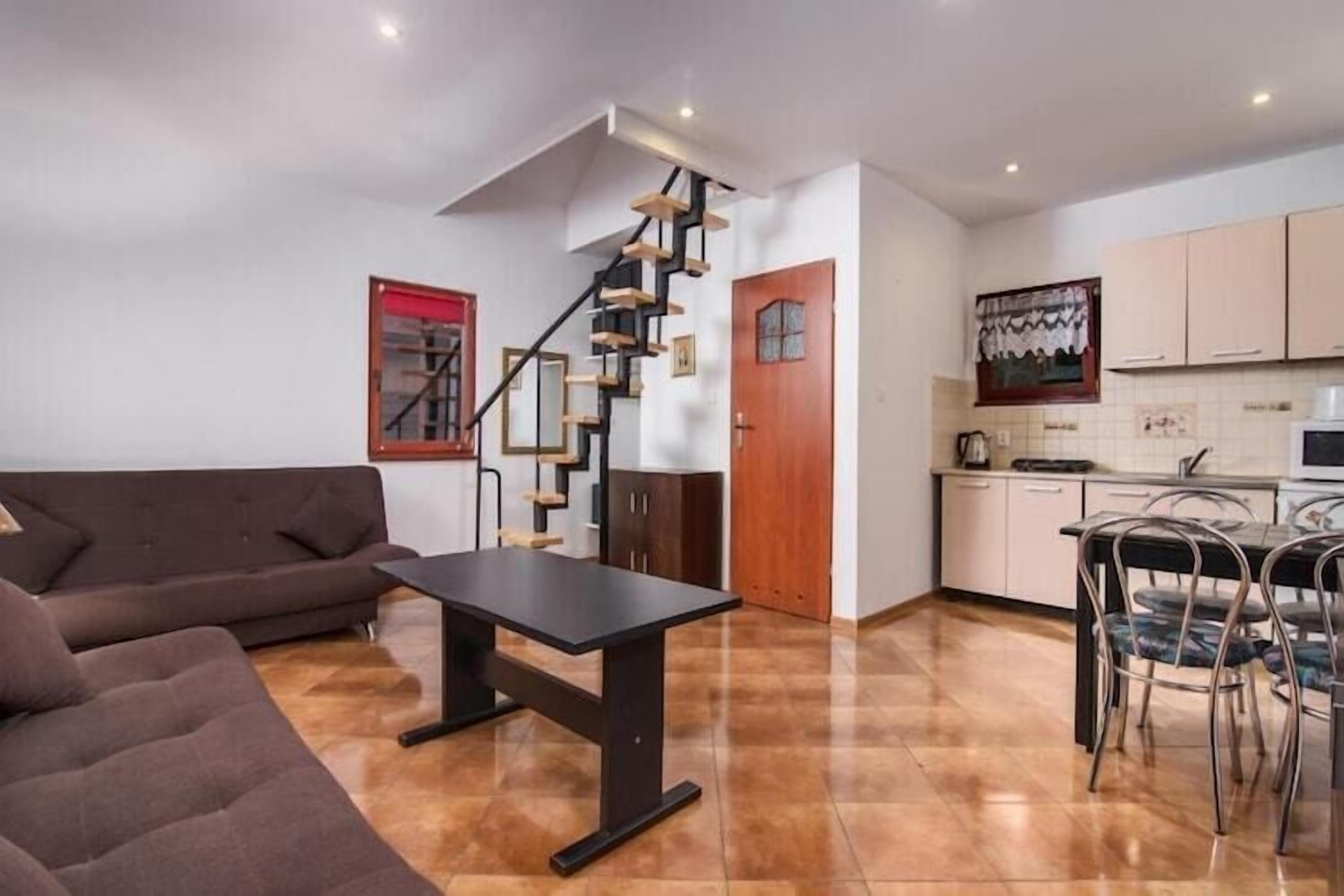 Un intérieur moderne comprenant un escalier, un canapé, une table à manger et un coin cuisine.