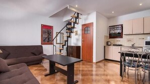 Een modern interieur met een trap, een bank, een eettafel en een keukenhoek.