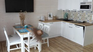 A modern kitchen with white cabinetry, a flat-screen TV, a microwave, and a patterned backsplash. - Large holiday homes with beautiful gardens (Pobierowo)