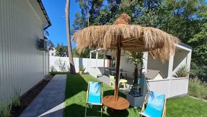 A backyard with a thatched umbrella, a small table, two chairs, and a potted plant. - Large holiday homes with beautiful gardens (Pobierowo)