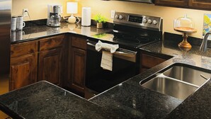 Una cucina con mobili in legno, un frigorifero in acciaio inossidabile, un forno a microonde, un forno e un lavello.