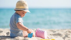 Ett barn leker med sandleksaker på en strand.