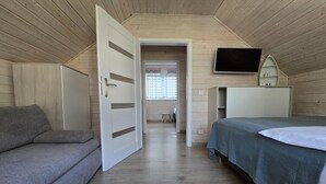 Ett rum med en säng, en soffa, en tv och en dörr som leder till ett annat rum.