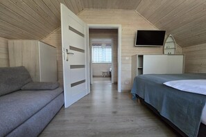 A room with a bed, a sofa, a TV, and a door leading to another room. - Comfortable houses with terraces (Pobierowo)