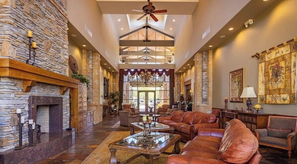 A spacious lobby with a stone fireplace, leather sofas, and a chandelier. - Experience Refined Desert Living At It's Best! (Mesa)