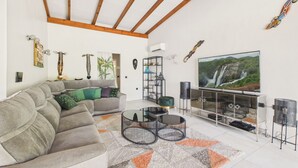 Una sala de estar con sofá, mesa de centro, televisor y elementos decorativos.