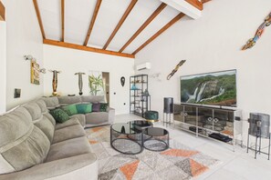 Ein Wohnzimmer mit einer Couch, einem Couchtisch, einem Fernseher und Dekorationselementen.