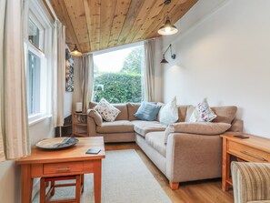 Een gezellige woonkamer met een beige bank, een houten salontafel en een bijzettafeltje van hout.