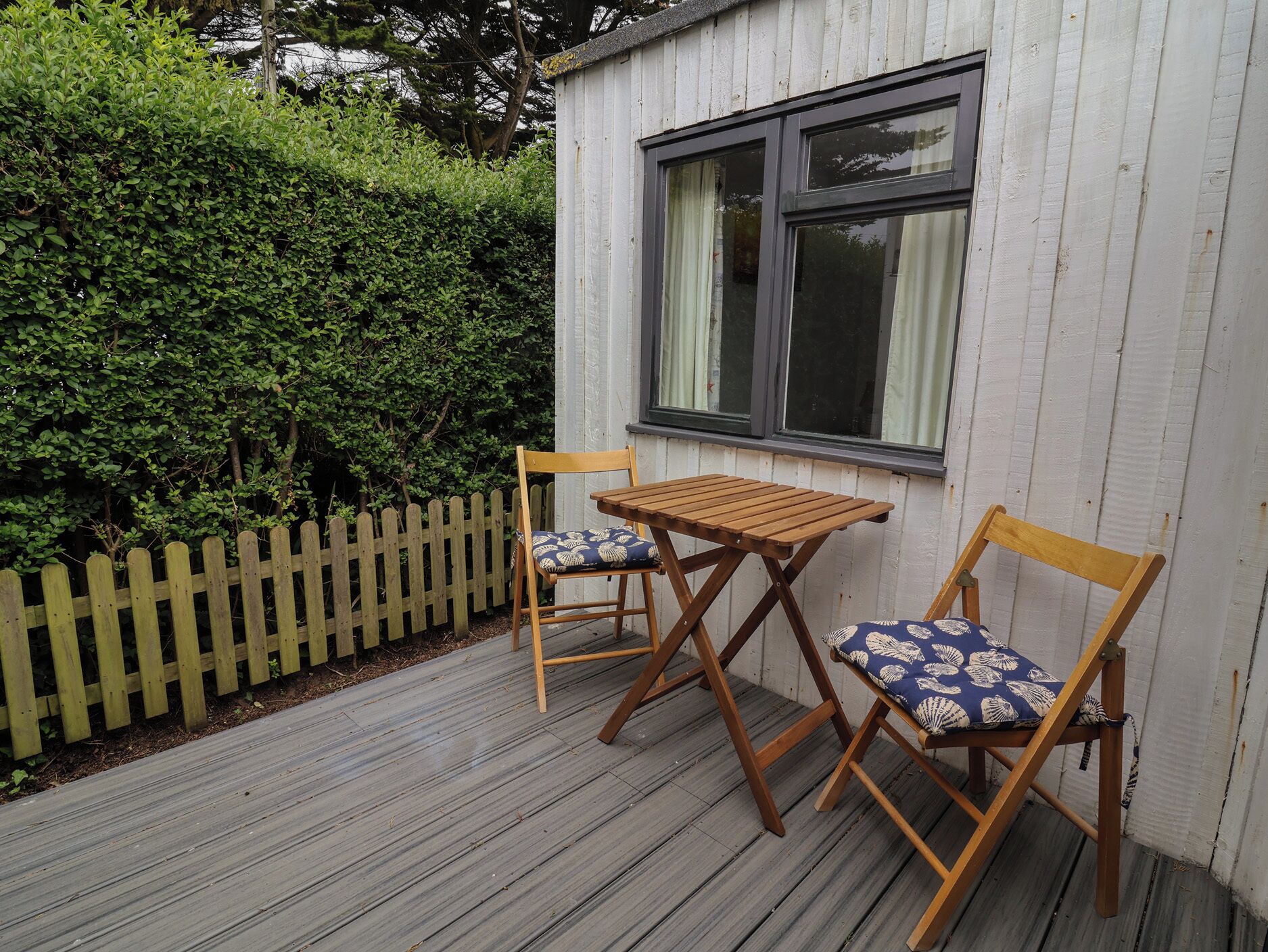 A wooden deck with two wooden chairs and a small table.