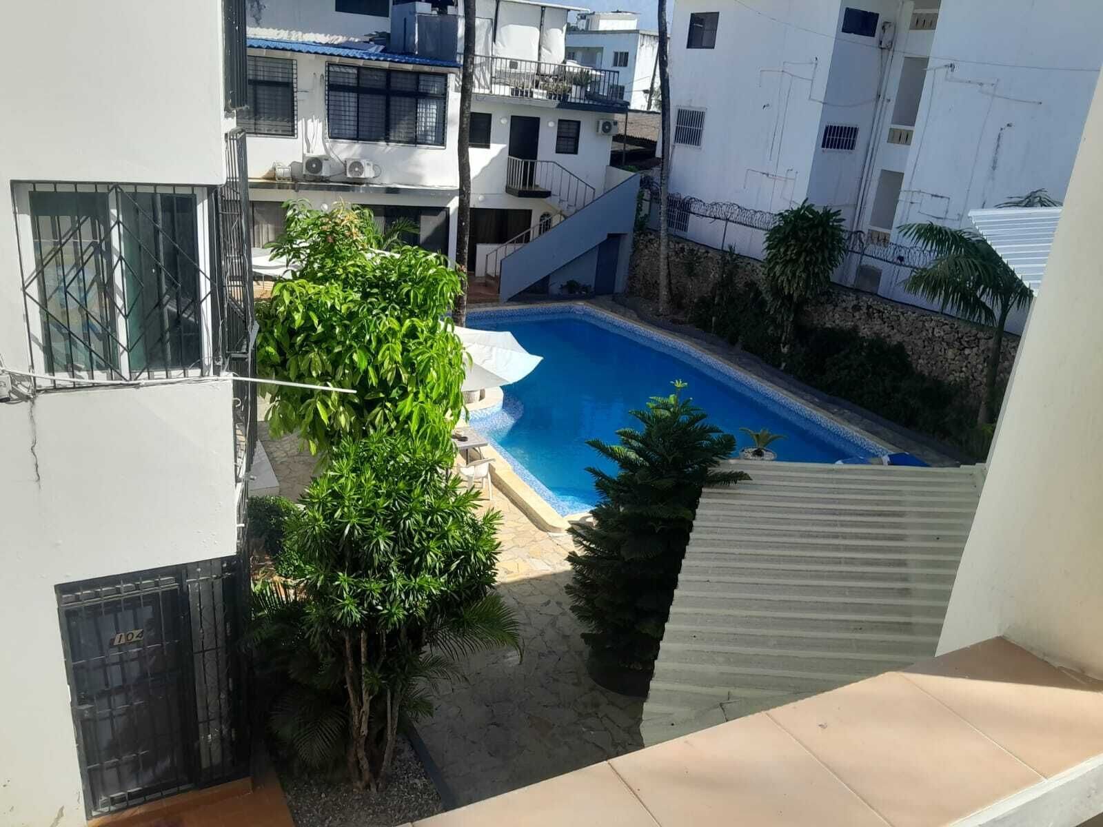 A residential building with a swimming pool, a staircase, and surrounding greenery.