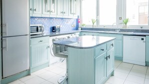 A kitchen with light blue cabinets, a central island, a microwave, and a sink. - Luxury Penthouse, next to Harrods (Londra)