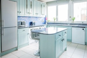 A kitchen with light blue cabinets, a central island, a microwave, and a sink. - Luxury Penthouse, next to Harrods (Londra)