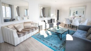 A modern living room with a sofa, armchairs, a coffee table, and a dining area with chairs and a table. - Luxury Penthouse, next to Harrods (Londra)