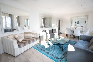 A modern living room with a sofa, armchairs, a coffee table, and a dining area with chairs and a table. - Luxury Penthouse, next to Harrods (Londra)