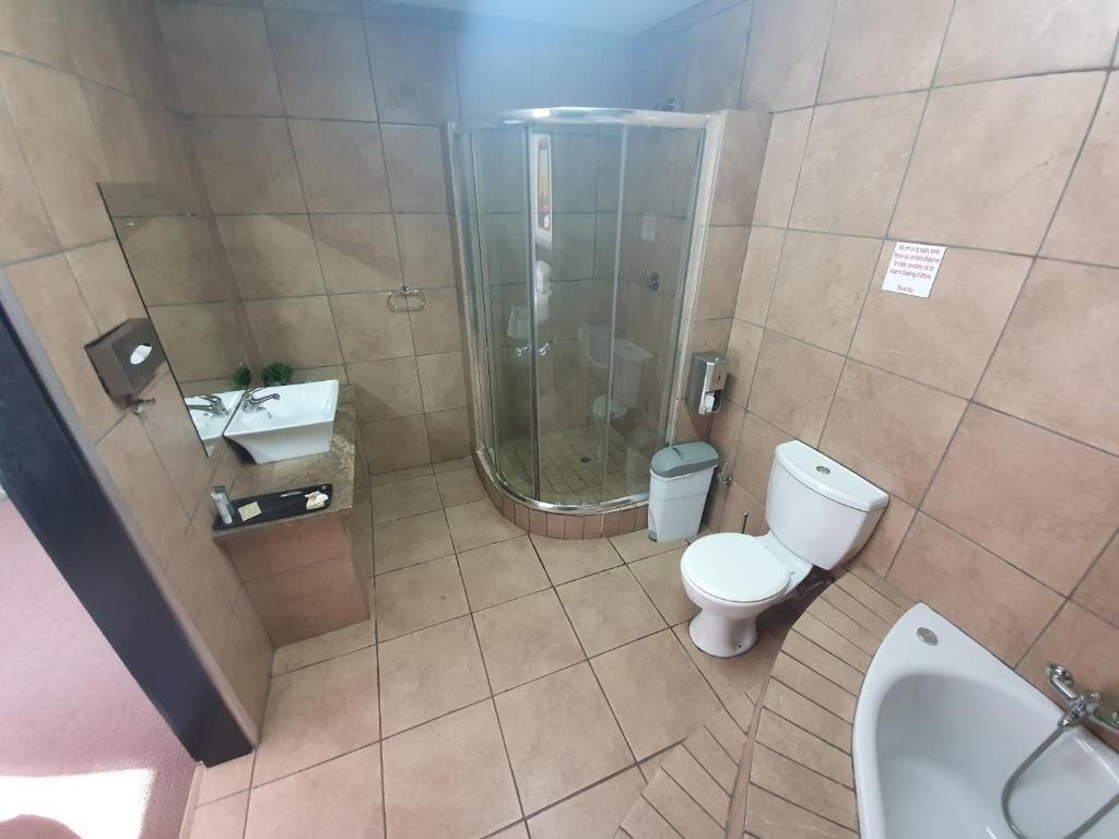 A bathroom with a glass-enclosed shower, a toilet, and a sink.