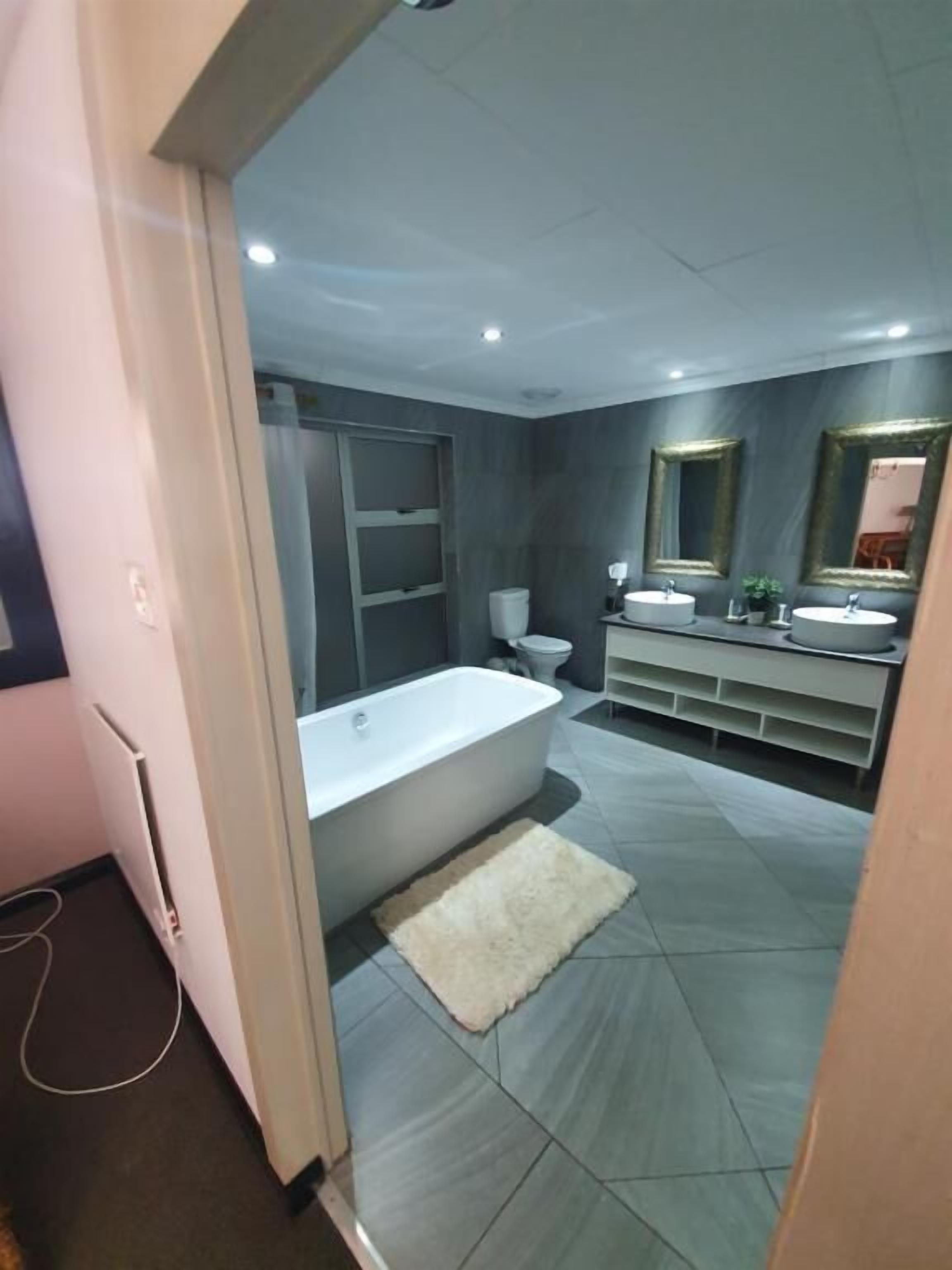 A modern bathroom with a bathtub, two sinks, and a vanity.
