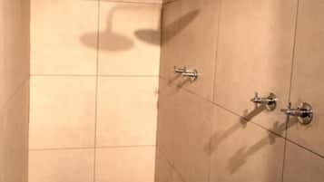 Une petite salle de douche carrelée, équipée d’un pommeau de douche à main et d’un robinet mural.