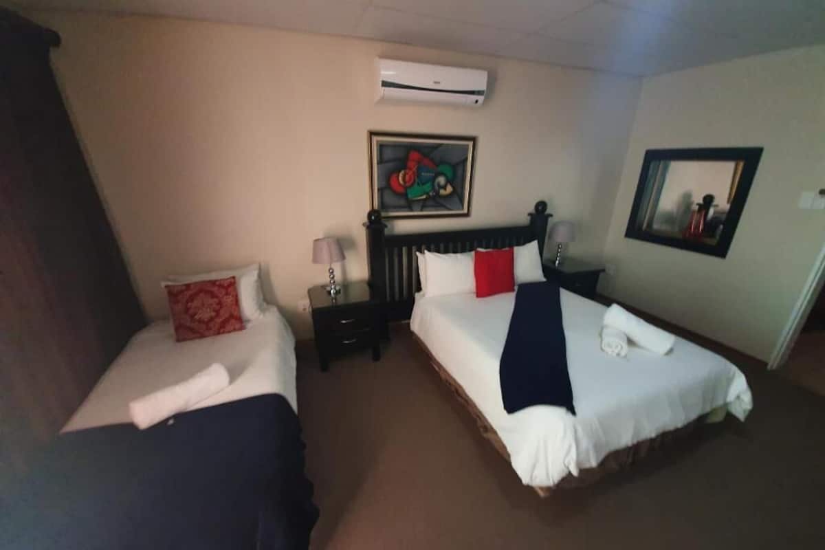 A hotel room with two beds, a nightstand, an air conditioning unit, and a framed picture on the wall.